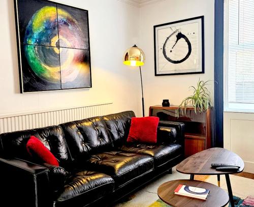 a living room with a black leather couch at No.2 Boutique Art Townhouse  in Lincolnshire
