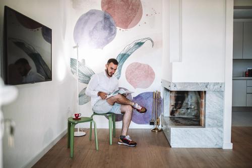 un hombre sentado en una silla en una sala de estar junto a una chimenea en Villa Ardura - island holiday residence **** Bol. Island Brač en Bol