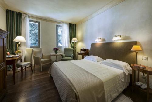 a hotel room with a bed and a table and chairs at Posta Donini 1579 - UNA Esperienze in San Martino in Campo
