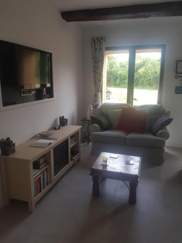 sala de estar con sofá y TV de pantalla plana en Grange Bouton d Or sleeps 2 quiet countryside location Boussac medieval town, en Malleret-Boussac