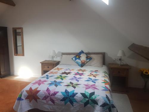 une chambre avec un lit avec une courtepointe colorée dessus dans l'établissement Grange Bouton d Or Quiet countryside location, à Malleret-Boussac