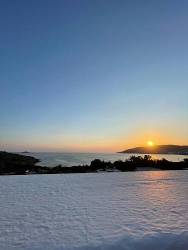 um pôr do sol sobre a água com o sol no céu em Villa Maniati Studios em Agios Petros