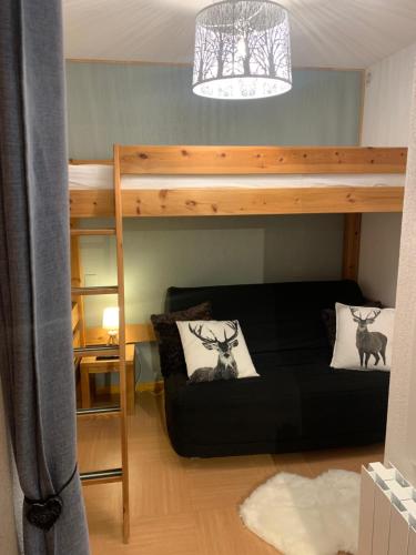 um pequeno quarto com um beliche e um sofá em Appartement les orres 1800 pied des pistes em Les Orres
