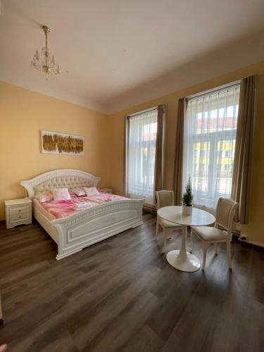 a bedroom with a bed and a table and windows at Apartmány vila Týniště in Týniště nad Orlicí