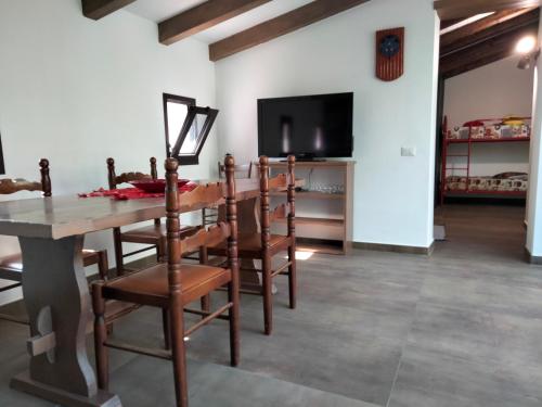 een eetkamer met een tafel en stoelen en een tv bij Cuntarati - Nature Tourism Simeto Etna in Bronte