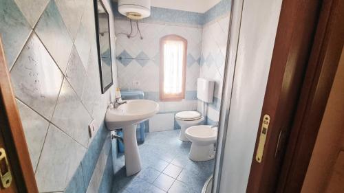 La salle de bains est pourvue d'un lavabo, de toilettes et d'une fenêtre. dans l'établissement La Baia Apartments, à Putzu Idu