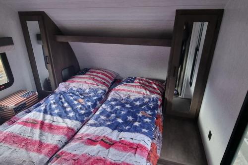 een bed in een kleine kamer met een bedsprei met Amerikaanse vlag bij US Camping Uckermark in Temmen-Ringenwalde