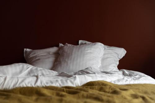 niepościelone łóżko z białą pościelą i poduszkami w obiekcie 2bis chambres d'hôtes w mieście Montreuil-sur-Mer