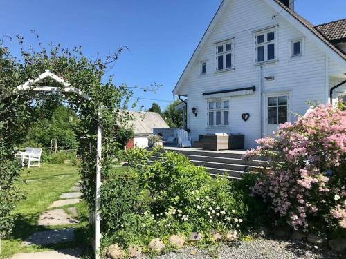 a white house with an arbor in the yard at Lenes hus in Halden