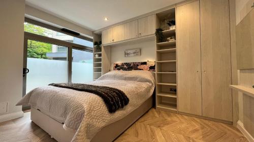 ein Schlafzimmer mit einem Bett und einem großen Fenster in der Unterkunft Nature's Retreat: 1B Home Christchurch, Dorset in Christchurch