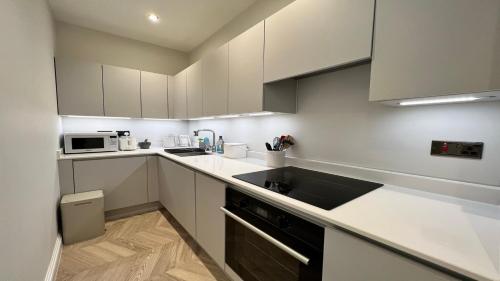 a white kitchen with a sink and a microwave at Nature's Retreat: 1B Home Christchurch, Dorset in Christchurch