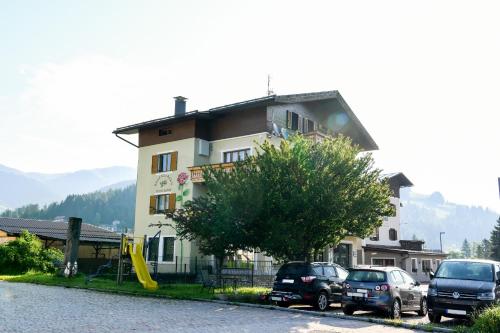 a building with cars parked in front of it at Guesthouse Rosengarten in Dobbiaco