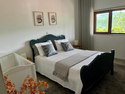 een slaapkamer met een bed met kussens en een raam bij Casa Mira Tâmega in Marco de Canavezes