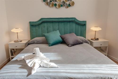 een bed met een groen hoofdeinde en een badjas bij Rooms AL-Zabut in Sambuca di Sicilia