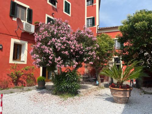a red building with trees and flowers in front of it at Hotel Villa Sermolli in Borgo a Buggiano
