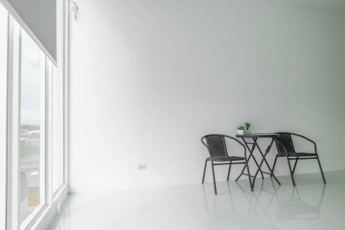 a table and chairs in a white room with a window at S1 Trang Hotel in Trang