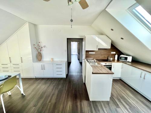 a large kitchen with white cabinets and a table at Holiday Apartment Žabovřesky in Hluboká nad Vltavou