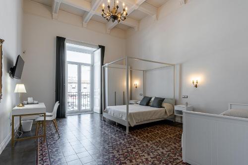a bedroom with a bed and a desk and a window at Il respiro di Encelado B&B in Catania