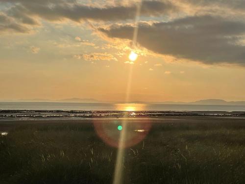 a sunset over a beach with the sun setting at Cosy Seaside Cottage in Allonby