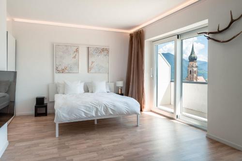 a white bedroom with a bed and a large window at Villa Maria Boutique Apartment St Pauls in Appiano sulla Strada del Vino