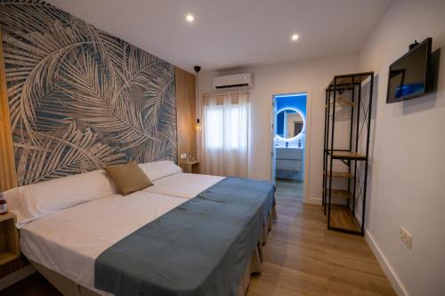 1 dormitorio con 1 cama y un mural en la pared en Hostal Royal Bliss en Punta Umbría