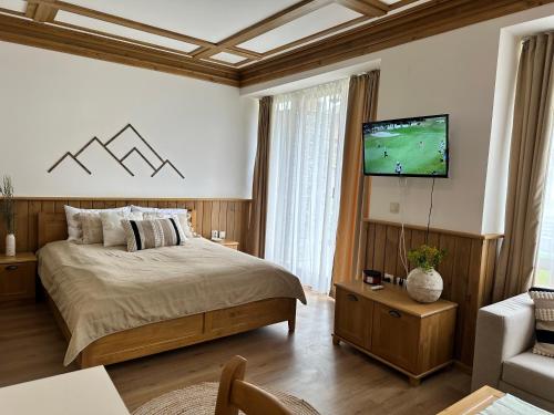 a bedroom with a bed and a flat screen tv at Pirin Golf & Spa Greenside Studio in Razlog