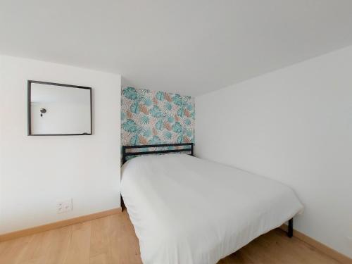 Schlafzimmer mit einem weißen Bett und einem Spiegel in der Unterkunft ° Appart 4 - Lunéville centre ° in Lunéville