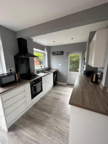 a kitchen with white cabinets and a stove top oven at Fabulous 3bed off street parking in Stafford