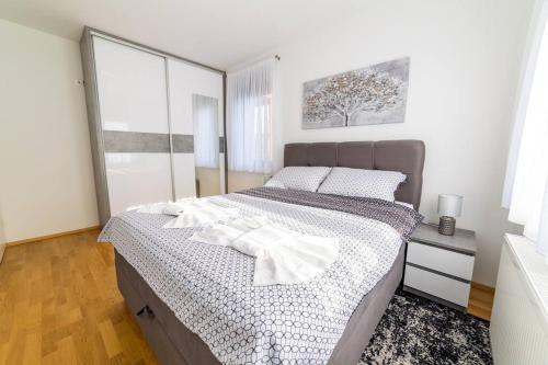 a bedroom with a large bed with white sheets at Apartman Lux in Virovitica