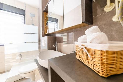 a bathroom with a toilet and a basket of towels at Apartman Lux in Virovitica