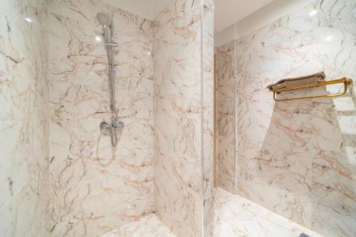 La salle de bains est pourvue d'une douche et d'un mur en marbre. dans l'établissement Résidence Coralia les orangers, à Marrakech