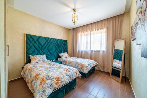 een slaapkamer met 2 bedden en een spiegel bij Résidence Coralia les orangers in Marrakesh