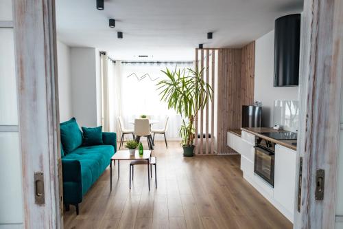 a living room with a blue couch and a kitchen at Apartament 2 Komfort in Słupsk