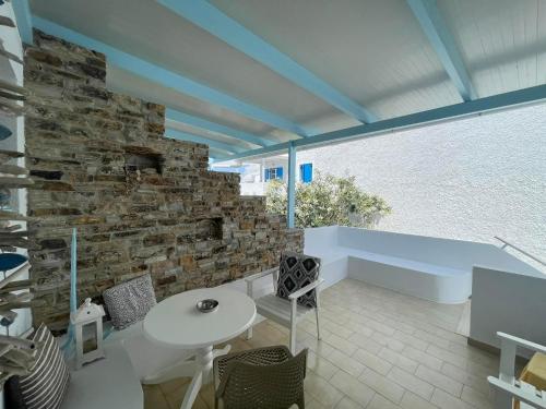Habitación con pared de piedra, mesa y sillas. en Yannis Maria Rooms, en Antíparos