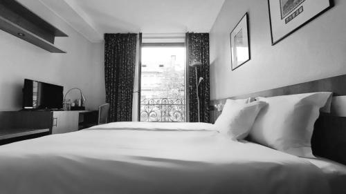 a bedroom with a large white bed and a window at HOTEL de la POSTE in Esch-sur-Alzette