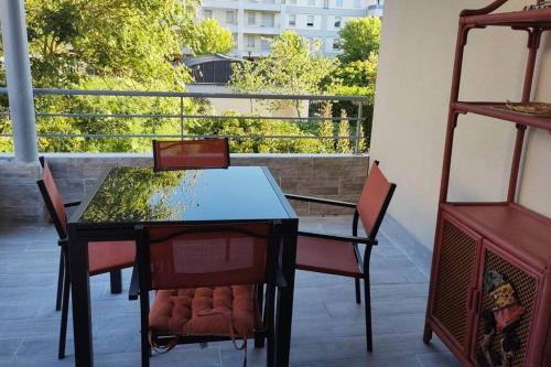 un tavolo nero e sedie sul balcone di Appartement 65 m² avec piscine. a Tours
