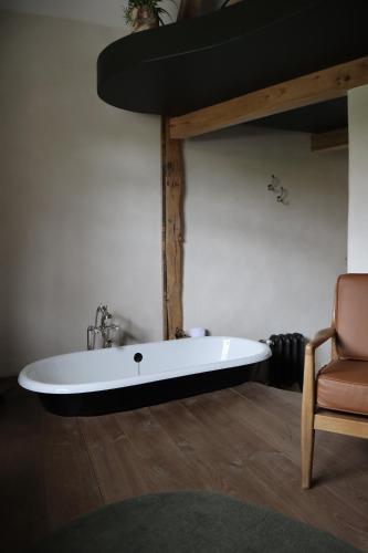 une baignoire installée dans une pièce avec une chaise dans l'établissement La Grenouillère, à Montreuil-sur-Mer