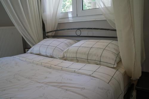 a bed with white sheets and pillows in front of a window at Zak's House in Platamonas
