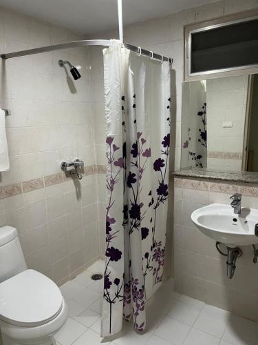 a bathroom with a shower curtain with a toilet and sink at Mall Suites Hotel in Bangkok