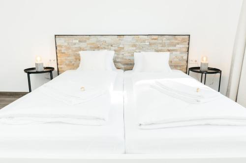 2 weiße Betten in einem Zimmer mit 2 Tischen in der Unterkunft HEIMATEL - Ferienwohnung Bergblick in Wangen im Allgäu