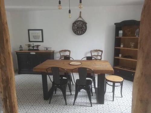 une table à manger avec des chaises et une horloge murale dans l'établissement Maison de charme, à Saint-Riquier
