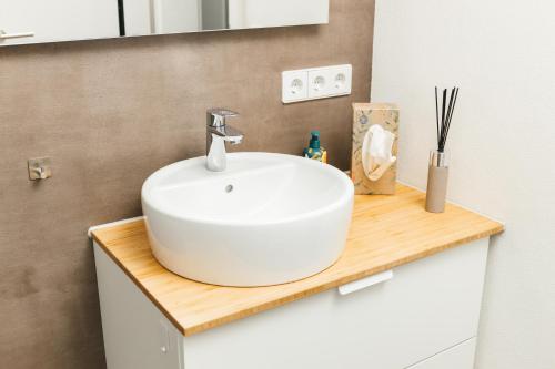 La salle de bains est pourvue d'un lavabo blanc sur un comptoir en bois. dans l'établissement HEIMATEL - Ferienwohnung Bergblick, à Wangen im Allgäu