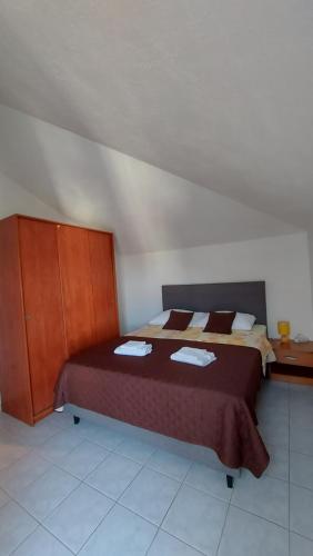 a bedroom with a bed and a wooden cabinet at Apartmani Galiot in Kaštela