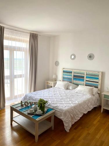 a white bedroom with a large bed and a table at Hotel Masseria Marziale in Brindisi