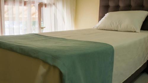 uma cama com um cobertor verde com uma janela em BELİS APART & PANSİYON em Kemer