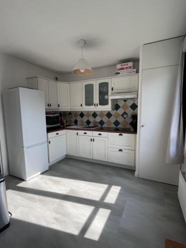 une cuisine avec des armoires blanches et un réfrigérateur blanc dans l'établissement Appartement Le Rochettois - VALGELON LA ROCHETTE - 25 mn station de ski Collet d'Allevard, à La Rochette