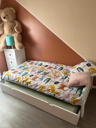 Una cama en un dormitorio con un osito de peluche en Appartement Nanterre, en Nanterre