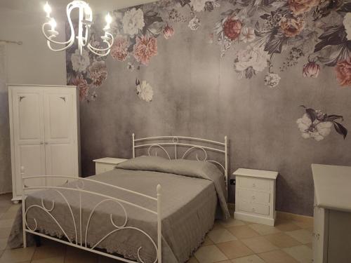 1 dormitorio con 1 cama con flores en la pared en Al Vecchio Pozzo en Campobello di Licata