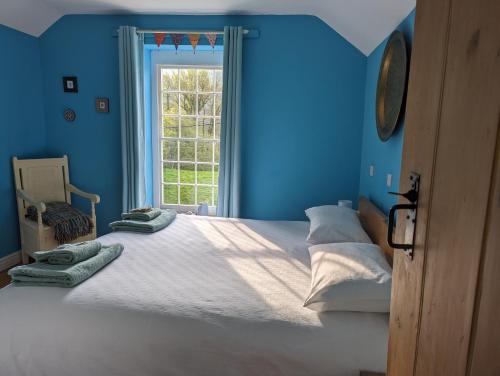 a blue bedroom with a large bed with a window at Isfryn Cottage in Aberangell