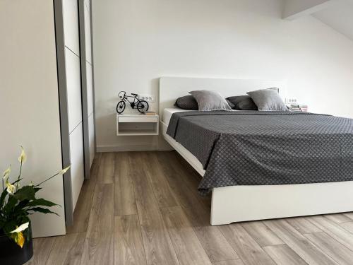 a white bedroom with a bed and a wooden floor at Holiday Home Bajlo in Zadar